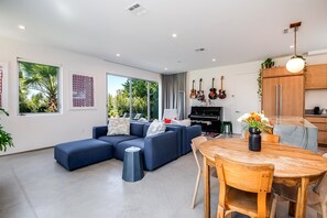 Relax in this spacious living area with a sofa, dining table, and entertainment setup featuring a piano and guitar.