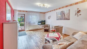 A living room with a sofa, armchairs, a TV, and a table with flowers. - 2 bedroom lovely apartment in Mirow (Mirow)