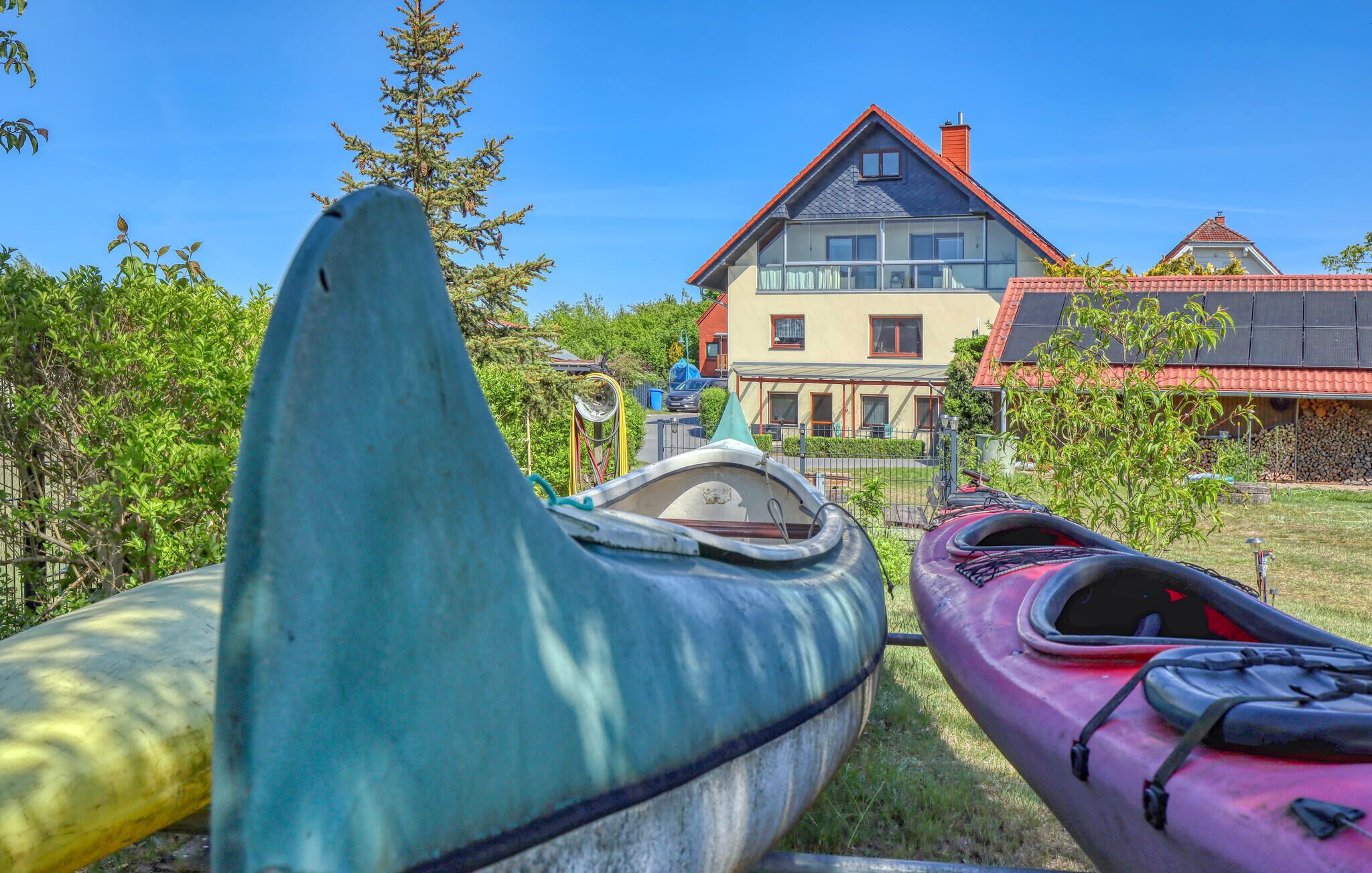 Two kayaks parked in a grassy area with a house in the background.