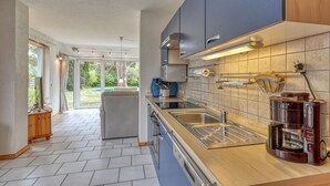 A modern kitchen with a large window, a built-in oven, and a coffee maker. - Ferienwohnung Pruchten (Pruchten)