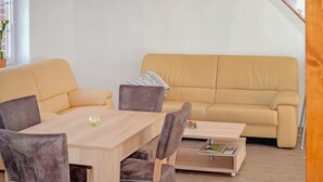 Un soggiorno con un divano beige, un tavolino in legno e un tavolo da pranzo con sedie.