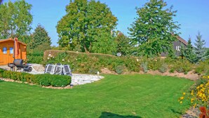Un giardino curato con prato, zona barbecue e un piccolo deposito.