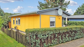 A yellow house with a satellite dish, a wooden fence, and a well-maintained hedge. - 2 bedroom awesome home in Wesenberg (Wesenberg)