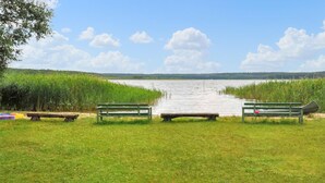 A lakeside view with two benches facing the water, a dock, and a grassy area. - 2 bedroom awesome home in Wesenberg (Wesenberg)