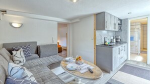 A compact living space with a sofa, a dining table set for two, a kitchen area with cabinets, and a shower. - Amazing apartment in Waren (Müritz) (Waren (Müritz))