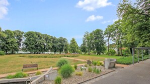 Un parc amb un camí pavimentat, bancs i una petita font.