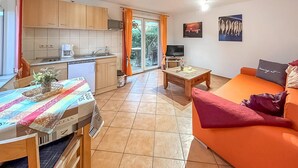 A compact living space with a kitchenette, a dining area, and a seating area with a sofa and a TV. - Ferienwohnung Kölpinsee/Usedom (Kölpinsee/Usedom)