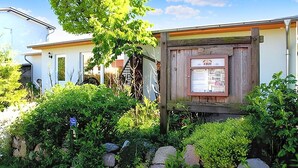 A rustic building with a wooden signboard, surrounded by lush greenery and rocks. - Ferienwohnung Kölpinsee/Usedom (Kölpinsee/Usedom)