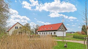 Ein ländliches Haus mit rotem Dach, umgeben von Feldern und Bäumen.