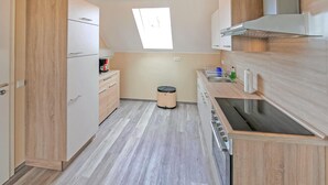 Eine kompakte Küche mit Holzausstattung, einem eingebauten Backofen und einem Fenster über der Spüle.