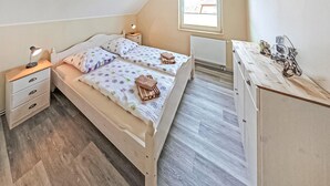 Ein Schlafzimmer mit zwei Betten, einem Nachttisch, einem Schreibtisch und einer Heizung.