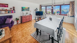 Un espace repas comprenant une table, des chaises, un canapé, un téléviseur et une bibliothèque.
