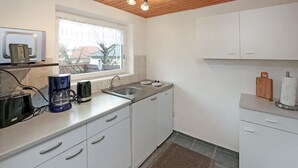 Eine kompakte Küche mit weißen Schränken, einer Spüle, einer Kaffeemaschine und einem Toaster.