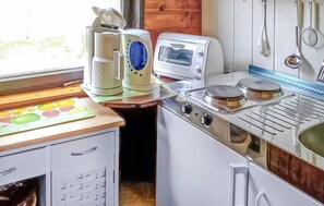 Een koelkast, een kookplaat, kookgerei, borden en bestek