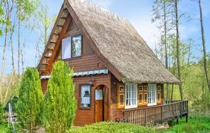 A wooden cabin with a steeply pitched roof, surrounded by trees. - Ferienhaus Rheinsberg OT Kagar (Rheinsberg OT Kagar)