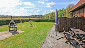 A backyard with a barbecue grill, a wooden fence, and a picnic table.