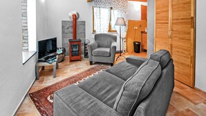 Een moderne woonkamer met een grijze bank, een televisie, een haard en een houten kledingkast.