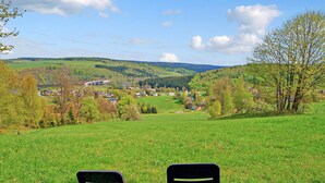 Two black chairs facing a scenic view of a village with a bridge in the distance. - Ferienwohnung Neuhausen (Neuhausen/Erzgeb.)