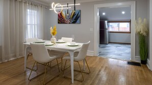 Un espace repas avec une table blanche, des chaises dorées et un luminaire moderne.