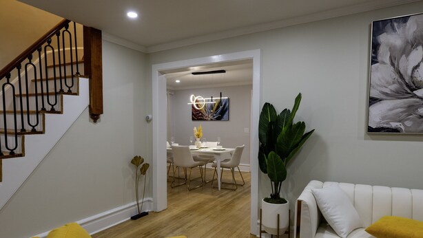 Un salon moderne avec un escalier, un coin repas et un grand tableau abstrait accroché au mur.