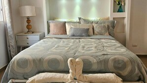 Une chambre à coucher comprenant un lit, une table de chevet, une lampe et une composition décorative faite de serviettes.