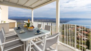 Un balcon avec une table dressée pour le petit-déjeuner, offrant une vue sur le paysage urbain de la côte.