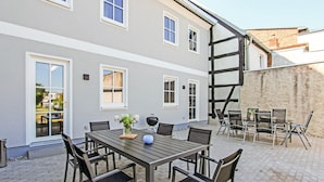 A patio with a table and chairs, a barbecue grill, and a view of a building with multiple windows and a chimney. - Gorgeous home in Ueckermünde (Seebad) (Ueckermünde (Seebad))