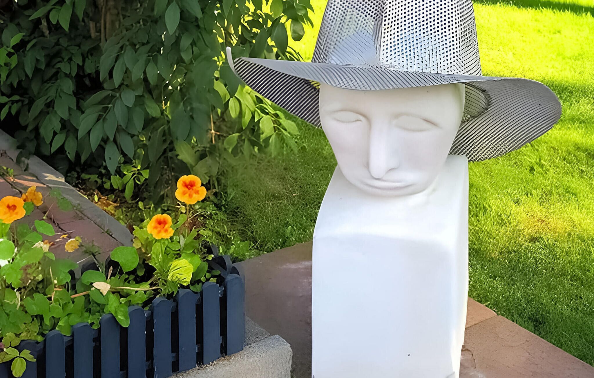 Un jardin agrémenté d’une statue blanche et d’un jardinier planté de fleurs.