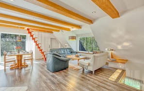 Um interior moderno com teto de madeira, escada, área de refeições e um espaço de estar.