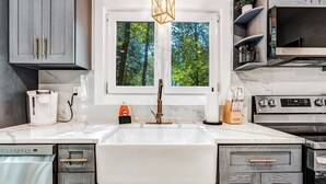 Une cuisine moderne dotée d’une grande fenêtre, d’appareils électroménagers intégrés et d’un plan de travail en marbre.