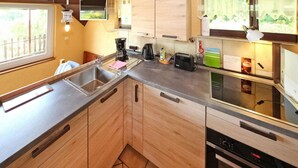 Een moderne keuken met houten kastjes, een roestvrijstalen spoelbak, een koffiezetapparaat en een inbouwoven.