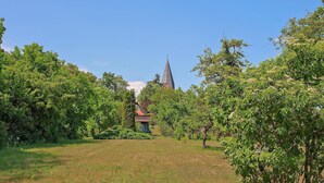 Een gazon met bomen en een gebouw met een puntige daklijn in de verte.