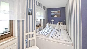 A bedroom with a bunk bed, striped curtains, a window with a view, and a wall-mounted lamp. - 1 bedroom awesome home in Malchow (Malchow)