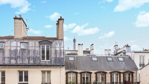 Une rangée de bâtiments de style européen, dotés de nombreuses cheminées et de lucarnes, se dressant sous un ciel d’un bleu éclatant.