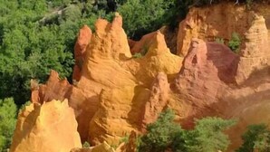 Paisagem com formações rochosas avermelhadas e vegetação verde.
