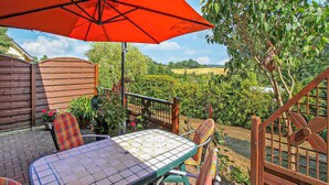 An outdoor patio with a table and chairs, surrounded by a wooden fence and a garden.