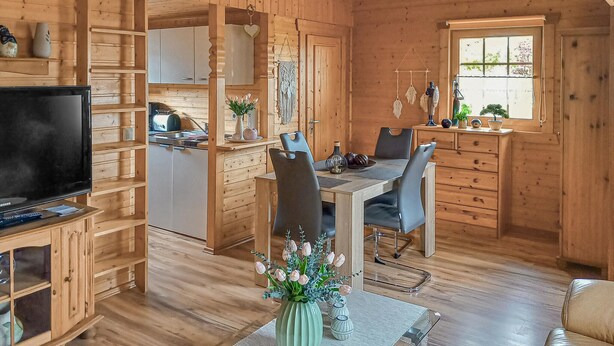 A cozy cabin interior with a dining area, kitchen, and a TV.