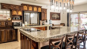A kitchen with granite countertops, wooden cabinets, and a large island with bar stools. - 5 Frogs Hotel Bucerias  (Bucerías)