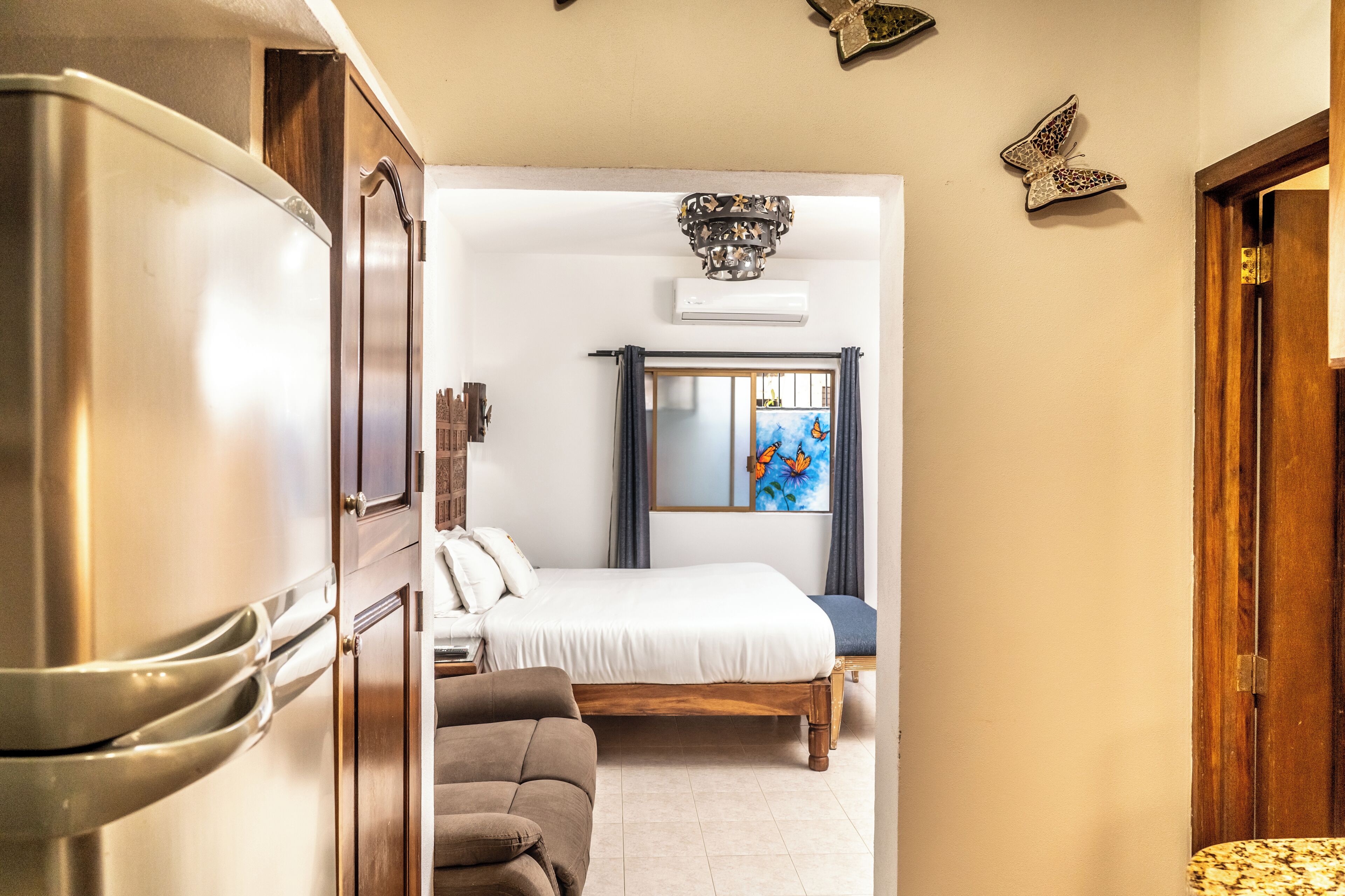 Un dormitorio con una cama, un armario de madera y un refrigerador moderno.