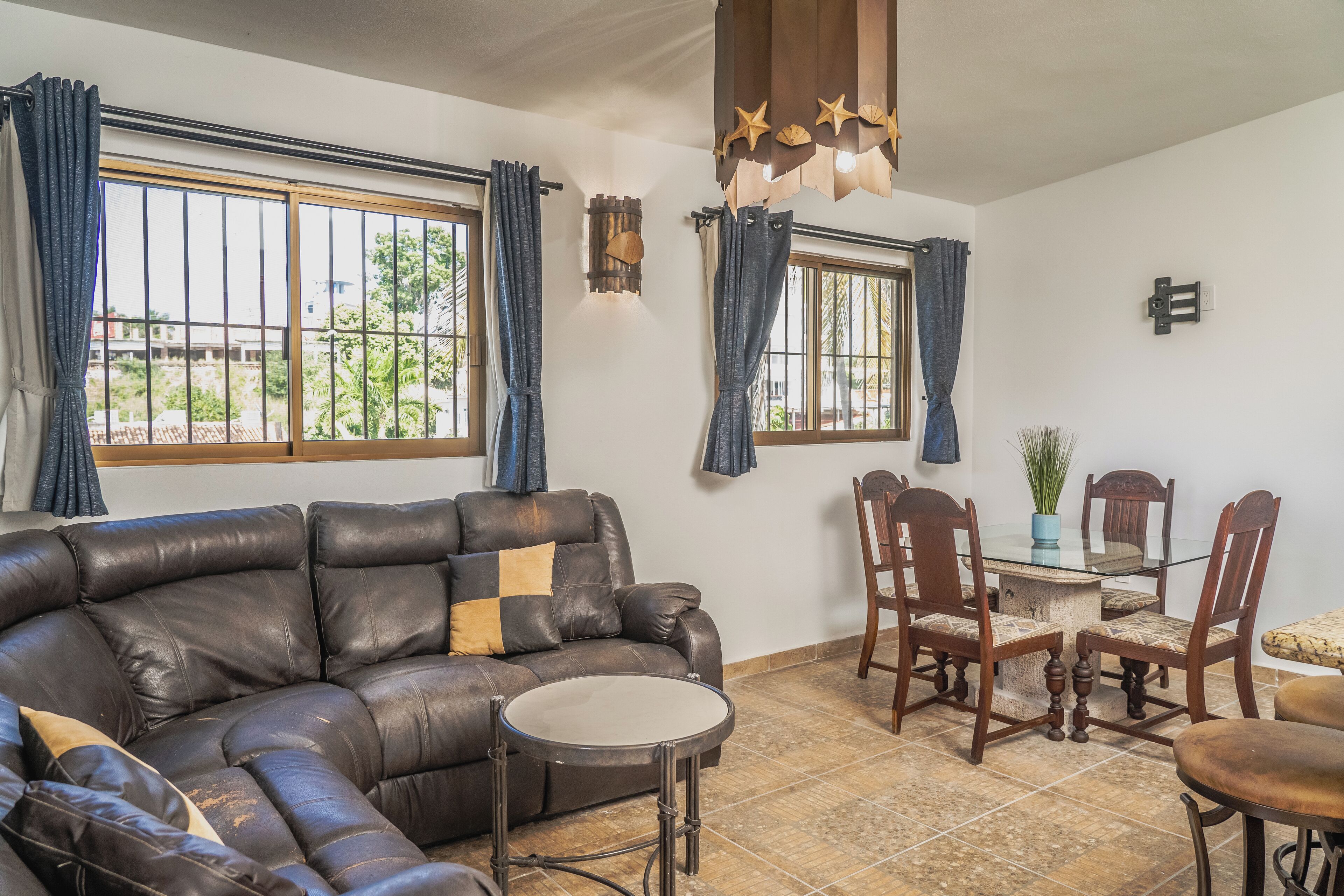 A living room with a leather sofa, a glass coffee table, and a dining area with wooden chairs and a table.