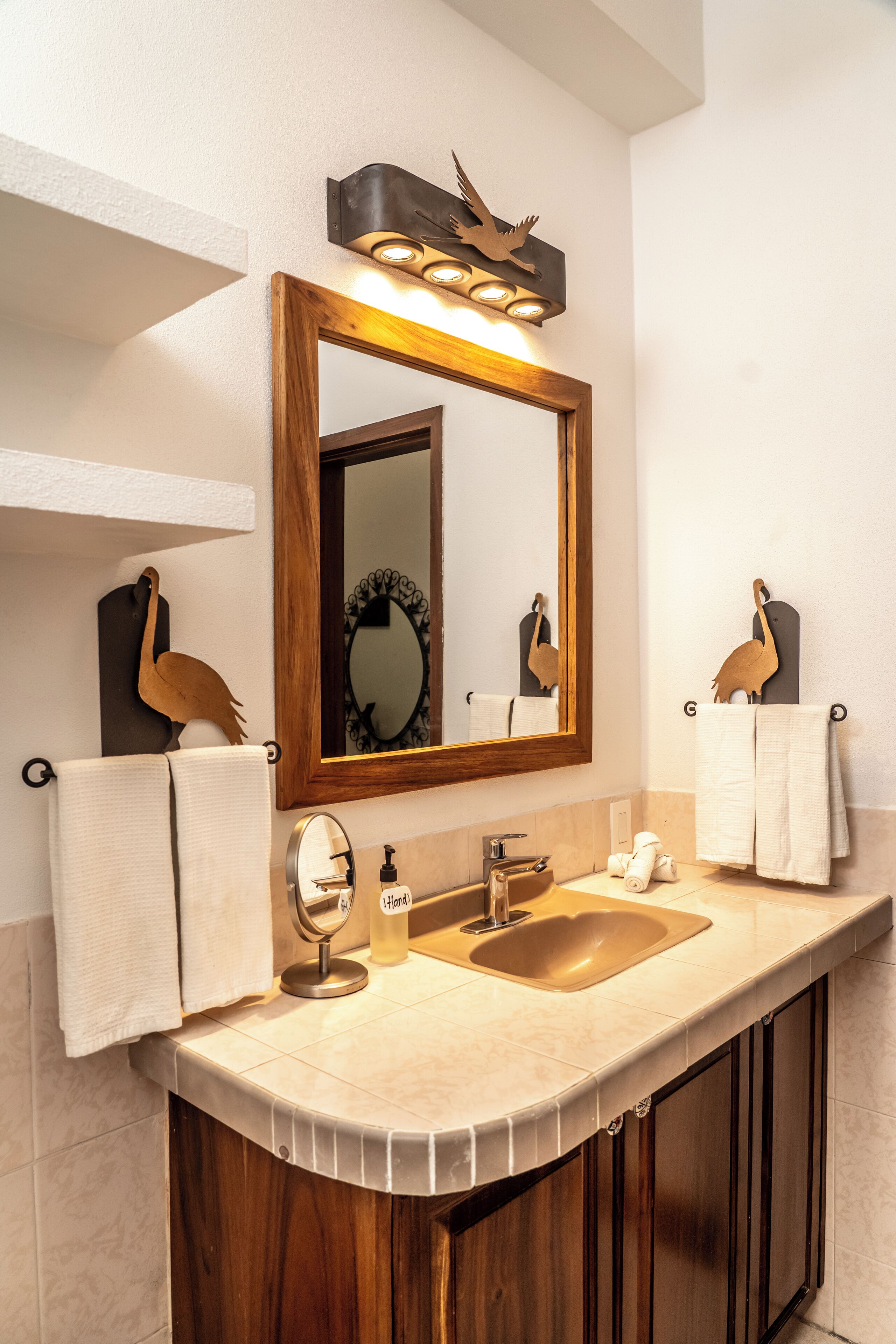 A bathroom with a wooden vanity, a large mirror, and two towels hanging on hooks.