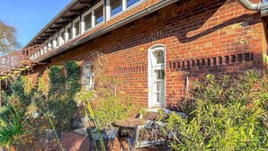A brick building with a covered outdoor seating area and potted plants. - Ferienwohnung Klocksin (Klocksin)