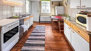 A compact kitchen with a stove, sink, and refrigerator. A window provides natural light, and a wooden floor adds warmth. - Ferienwohnung Klocksin (Klocksin)