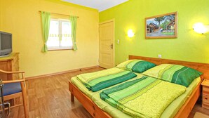 Una habitación con cama, televisión, escritorio y ventana con cortinas.
