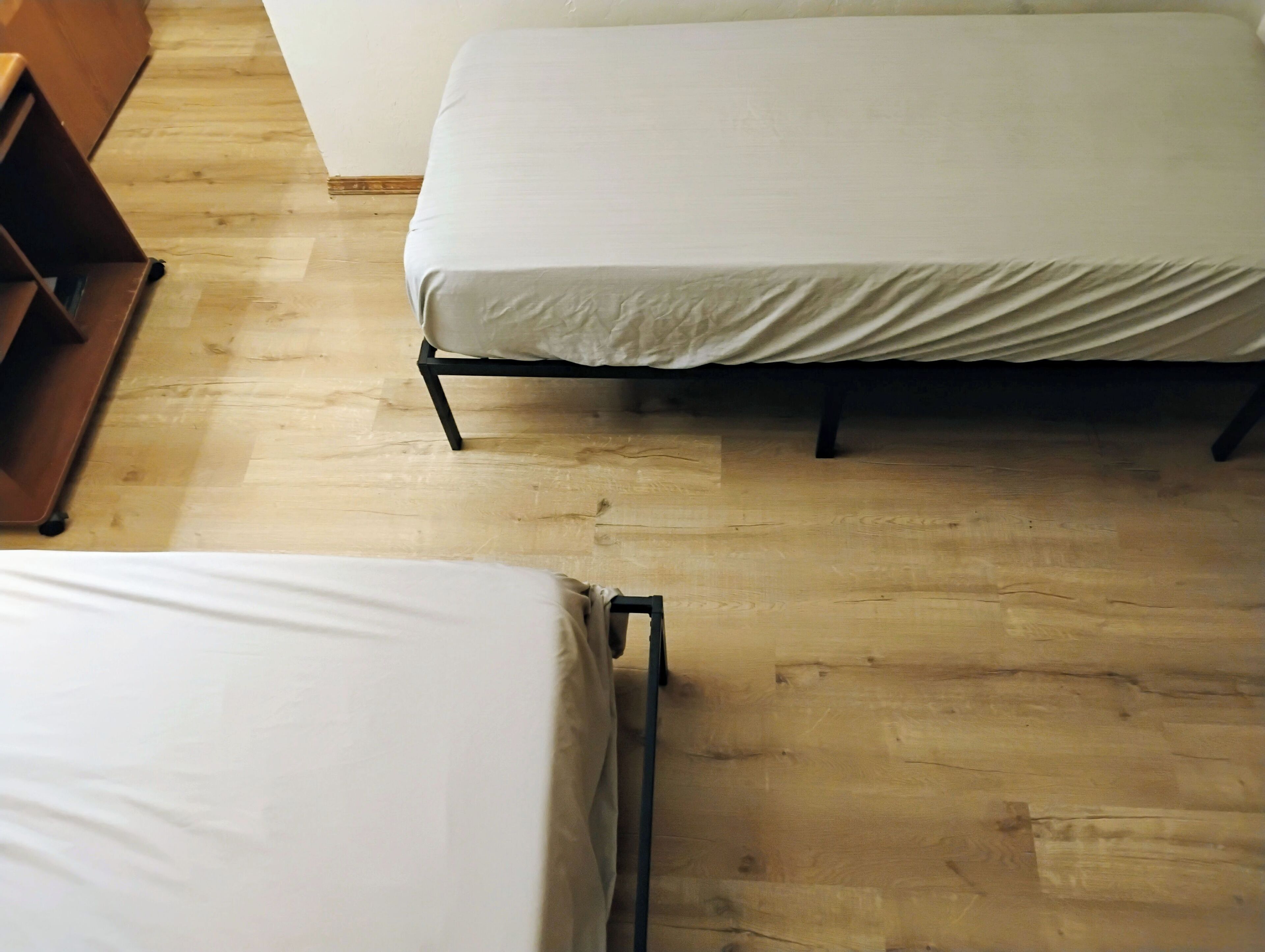 A room with a bed, a bench, and a wooden floor.