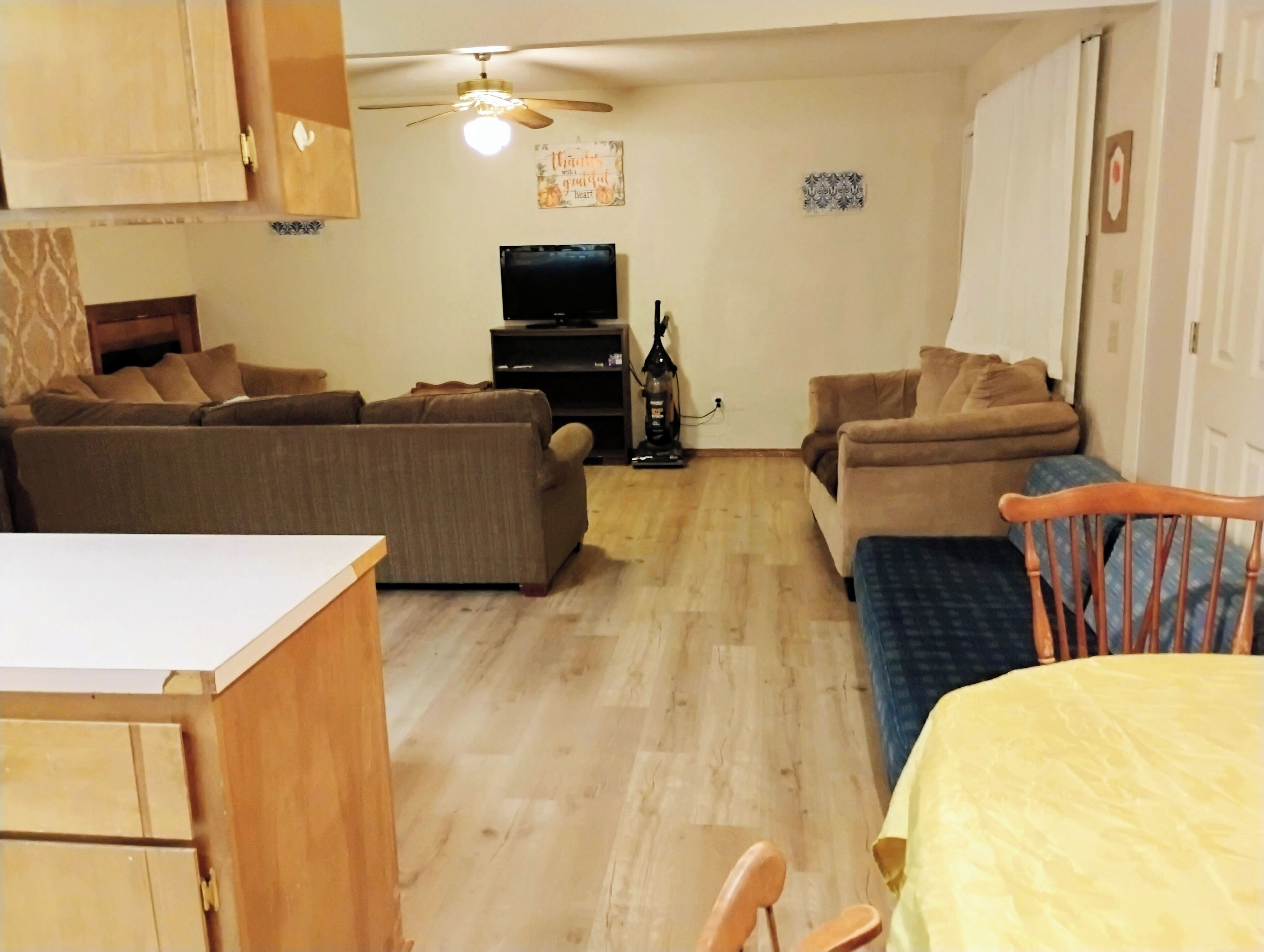 A living room with a sofa set, a television, and a ceiling fan.