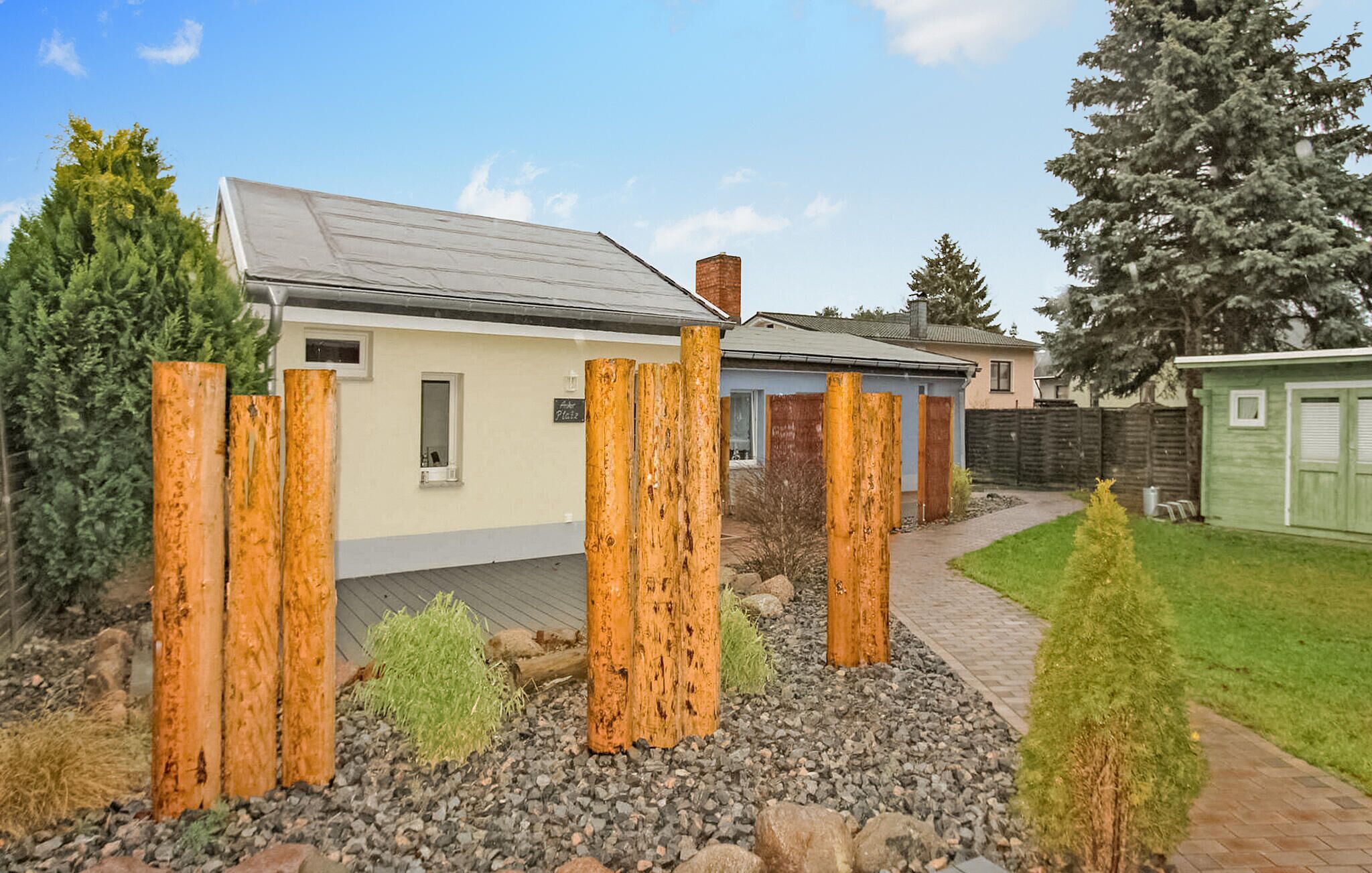 A house with a grey roof, a small attached garage, and a wooden fence in the front yard.