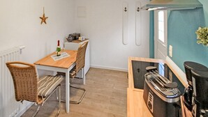 Une cuisine compacte équipée d’un grille-pain, d’une bouilloire et d’une petite table à manger avec des chaises.