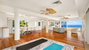 A spacious living area with wooden flooring, a yoga mat, and a view of the ocean.