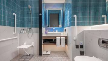 A modern bathroom with blue tiles, a white sink, a mirror, a shower, and a toilet.